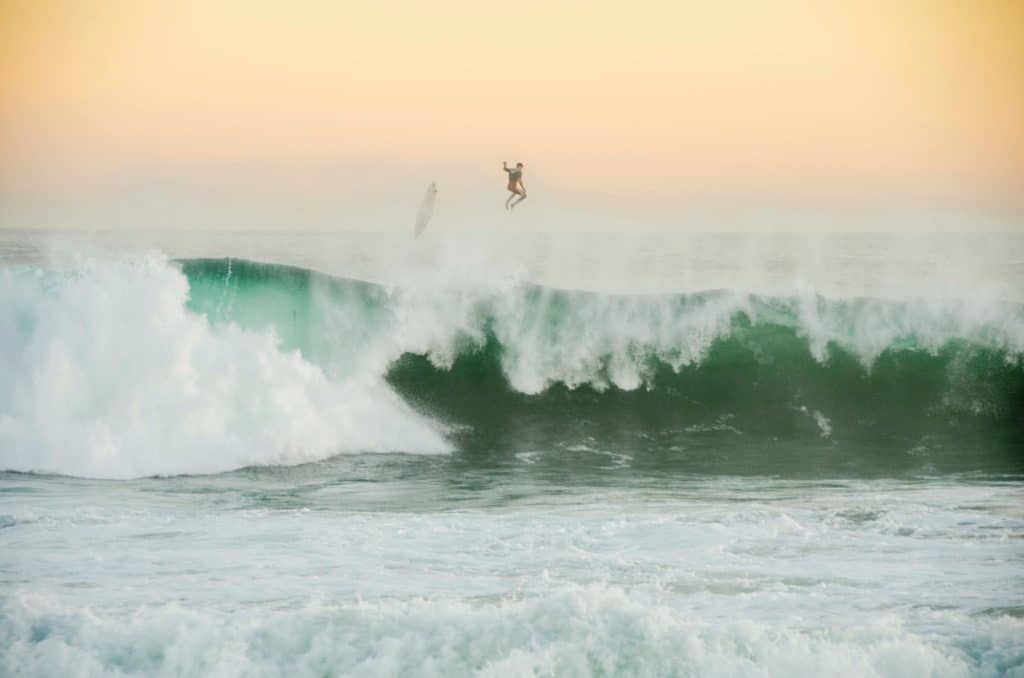 a surfer and his board flying above the wedge: a large, green, barreling wave at newport beach 