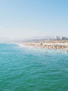 beach goers play in the turquoise water on a warm day in santa monica