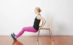 A woman does tricep dips on a chair