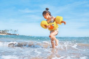 Girl in duck floatie plays at one of the best beaches for kids.
